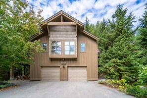 A two-story wooden house with a garage, surrounded by trees. - Near Gondola & Lake | Private Hot Tub| Free Ski Shuttle & Parking (Whistler)