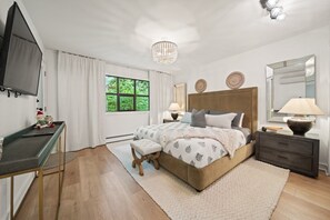 A bedroom with a large bed, a desk, a television, and a window with curtains. - Near Gondola & Lake | Private Hot Tub| Free Ski Shuttle & Parking (Whistler)