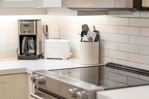 Eine Küche mit Kaffeemaschine, Toaster und Besteckhalter auf der Arbeitsfläche.