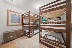 A bunk bed room with a framed picture on the wall, a small cabinet, and a patterned rug. - Near Gondola & Lake | Private Hot Tub| Free Ski Shuttle & Parking (Whistler)