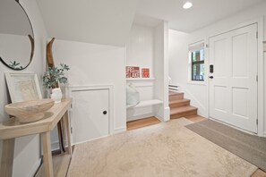 A hallway with a wooden bench, a mirror, a vase with a plant, and a door with a sign. - Near Gondola & Lake | Private Hot Tub| Free Ski Shuttle & Parking (Whistler)