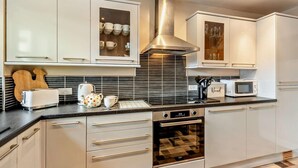 A modern kitchen with white cabinetry, a stainless steel range hood, a microwave, and a built-in oven. - 3 Bed in Morpeth (oc-91148) (Rothbury)