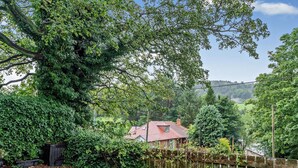 A residential area with a house, a wooden fence, and a large tree. - 3 Bed in Morpeth (oc-91148) (Rothbury)
