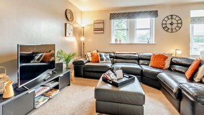 A living room with a TV, sofa, ottoman, and a bookshelf. - 3 Bed in Morpeth (oc-91148) (Rothbury)