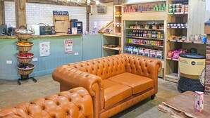 En ombonad inredning med en lädersoffa, en plats för att brygga kaffe och hyllor fyllda med snacks och drycker.