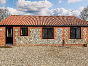A brick building with a tiled roof, stone wall accents, and a gravel driveway. - 2 Bed in Norwich (oc-91298) (Corpusty)