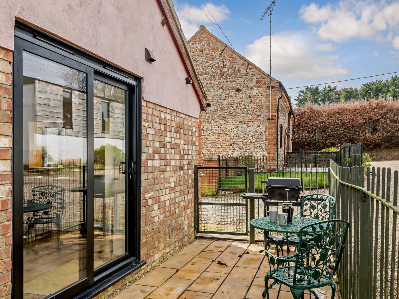 A patio with a table and chairs, a glass door, and a stone wall.