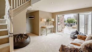 Eine Treppe führt zu einem Wohnbereich mit einer Couch, einem Tisch mit einer Lampe und Blick auf eine Terrass.'