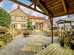 A stone house with a wooden deck and a stone wall.