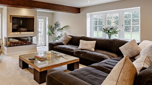 Ein Wohnzimmer mit Kamin, einer Couch, einem Couchtisch und einem großen Fenster.