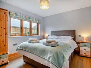 Una camera da letto con un letto, comodini, un armadio, una finestra con tende e una lampada a soffitto.
