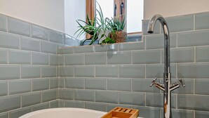 A bathroom with a white bathtub, a wooden tray, and a modern faucet. - 2 Bed in Axbridge (oc-91358) (Compton Bishop)