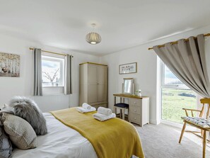 Ein Schlafzimmer mit Bett, Schreibtisch, Kleiderschrank und Blick ins Freie.