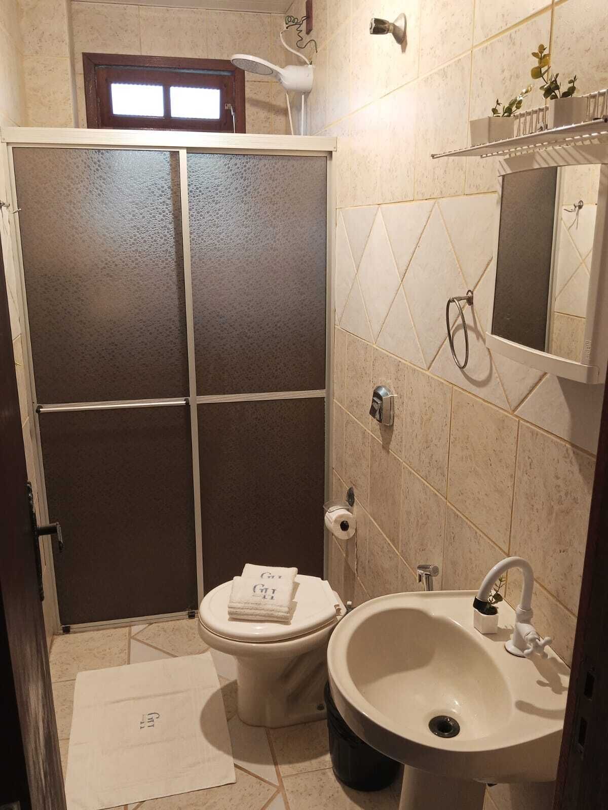 Casa de banho com sanita, lavatório e chuveiro.