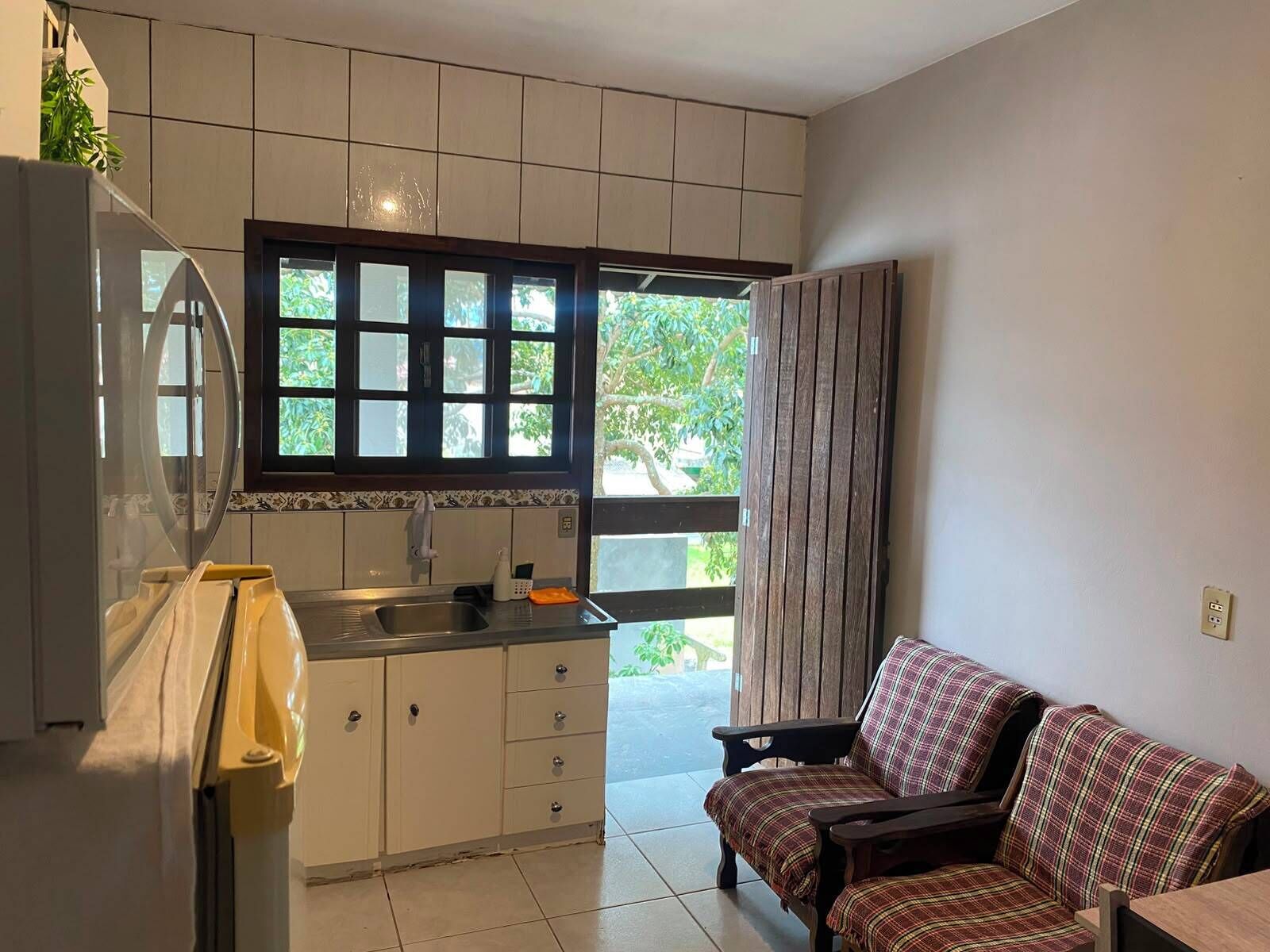 A compact kitchen with a window, a sink, and a dining area with a sofa.