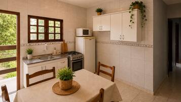 Uma cozinha com mesa de jantar, cadeiras, fogão, micro-ondas, armários e plantas em vasos.