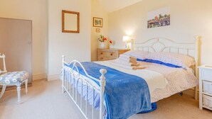 Ein Schlafzimmer mit einem Einzelbett, Nachttischen, einem Sessel und einer Tür.