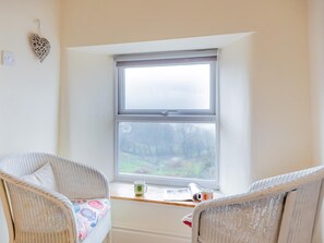 A room with two wicker chairs, a window with a view of a forest, and a small table with a mug and a book. - 2 Bed in Matlock (oc-91398) (Wirksworth)