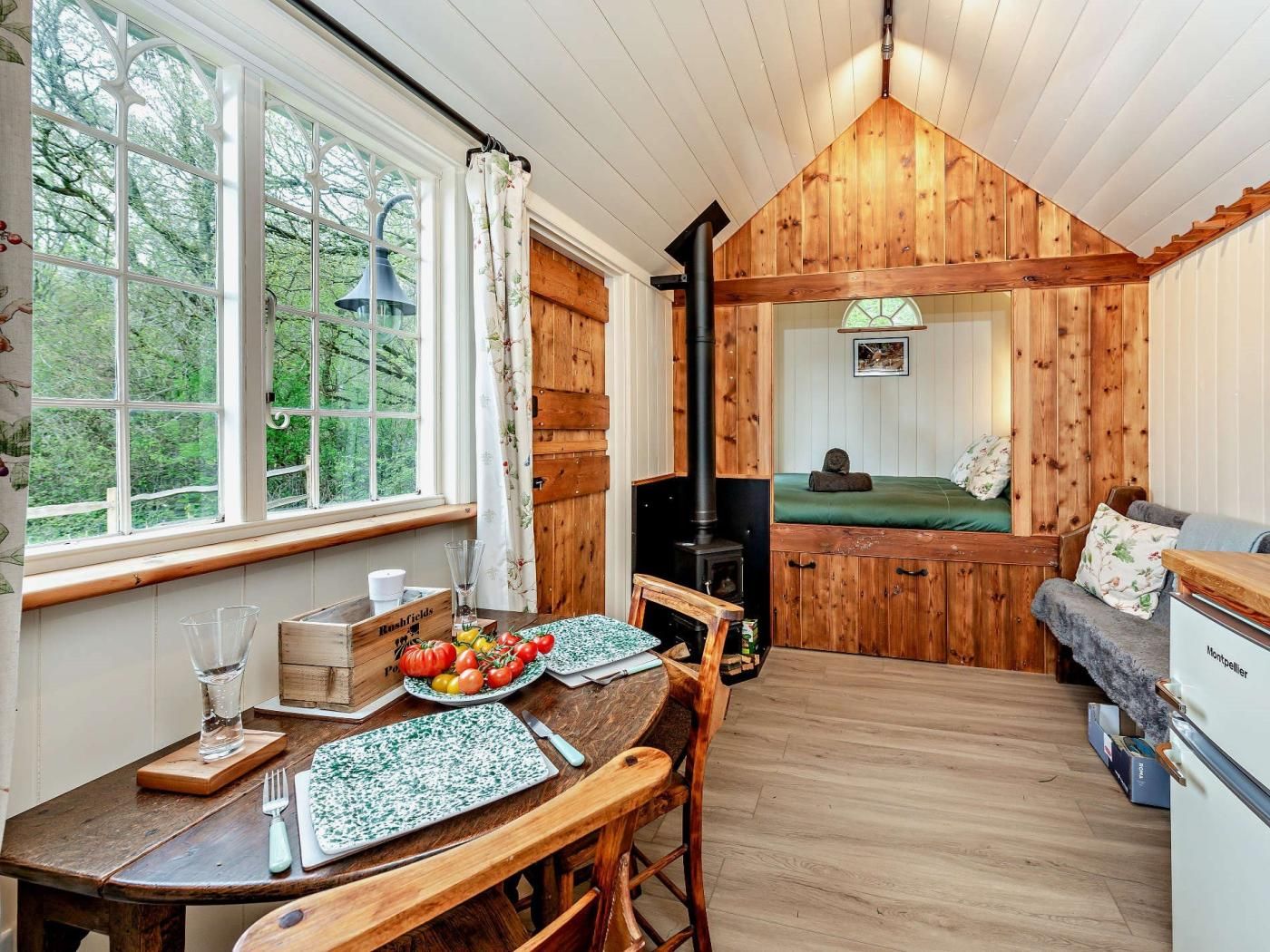 A cozy cabin interior with a dining area, a fireplace, and a view of the outdoors.
