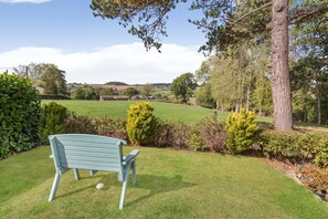 A bench in a grassy area with a view of a rural landscape. - 2 Bed in Exeter (oc-90455) (Tedburn Saint Mary)