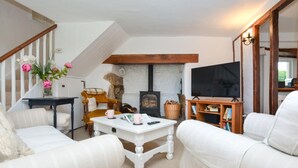 A cozy living room with a fireplace, a television, and a staircase. - 2 Bed in Exeter (oc-90455) (Tedburn Saint Mary)