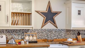 A kitchen with white cabinets, a star decoration, a tiled backsplash, and various kitchen items. - 2 Bed in Consett (oc-90576) (Shotley Low Quarter)