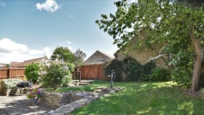A stone wall, a wooden fence, a grassy yard, and a building with a sloped roof. - 3 Bed in Richmond (oc-90578) (Catterick)