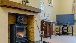 A living room with a stone fireplace, a television, and a red rug. - 3 Bed in Richmond (oc-90578) (Catterick)