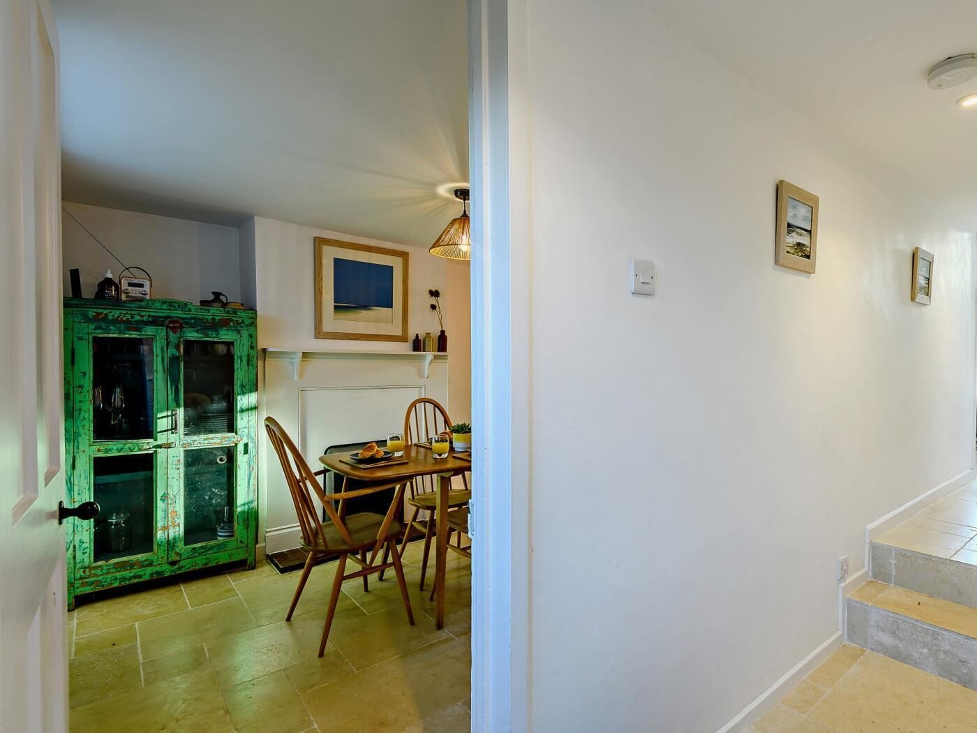 Un coin repas avec une table et des chaises, un meuble vert et un tableau accroché au mur.