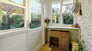 A corner room with a white door, a window with a view of greenery, a wicker basket, and a stone wall. - 2 Bed in Great Walsingham (oc-90535) (Little Walsingham)