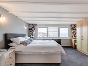 Ein Schlafzimmer mit Bett, Nachttischen, einem Fenster mit Vorhängen und Blick auf die Stadt.