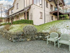 Una casa de dues plantes amb mur de pedra i camí d'accés de grava.