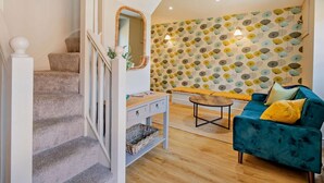 Ein Wohnzimmer mit Treppe, Sofa, Couchtisch und einer Wand mit Muster.
