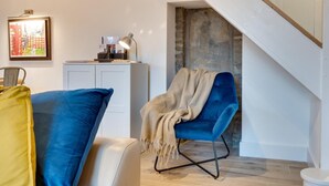 A modern living room with a blue armchair, a yellow pillow, and a desk with a lamp. - 3 Bed in Hawes (oc-90749) (Hawes)