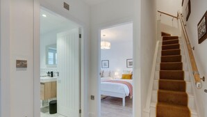 A modern interior with a staircase, a bedroom with a bed and a nightstand, and a bathroom with a sink and mirror. - 3 Bed in Hawes (oc-90749) (Hawes)