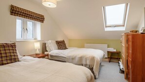 Un dormitorio con dos camas, una ventana, un radiador y un armario de madera.