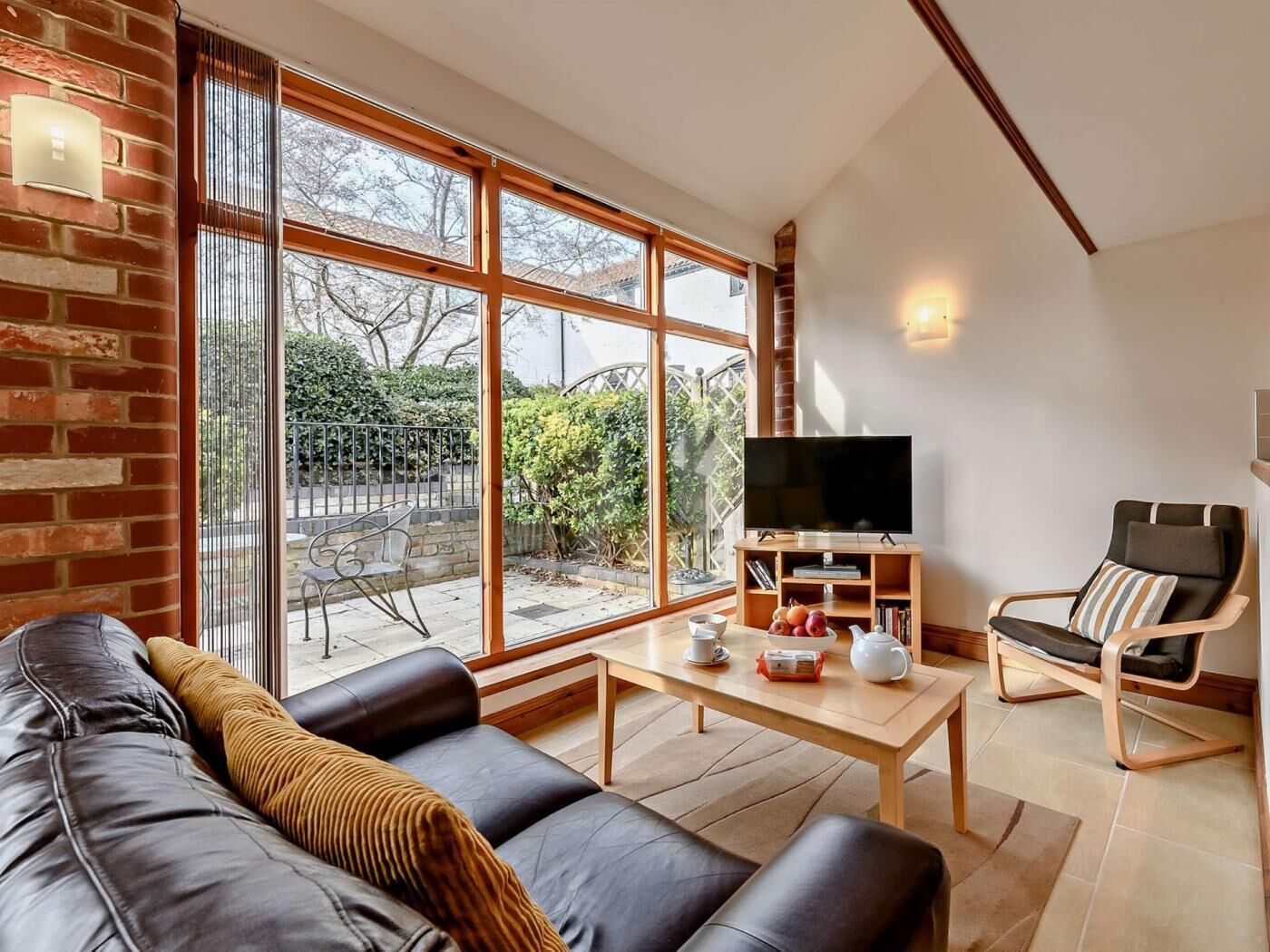 Un salon moderne avec un canapé en cuir, une table basse, un meuble pour la télévision et un fauteuil.
