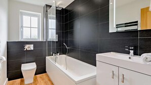 A modern bathroom with a bathtub, toilet, and vanity. - 3 Bed in Whitstable (oc-91063) (Whitstable)