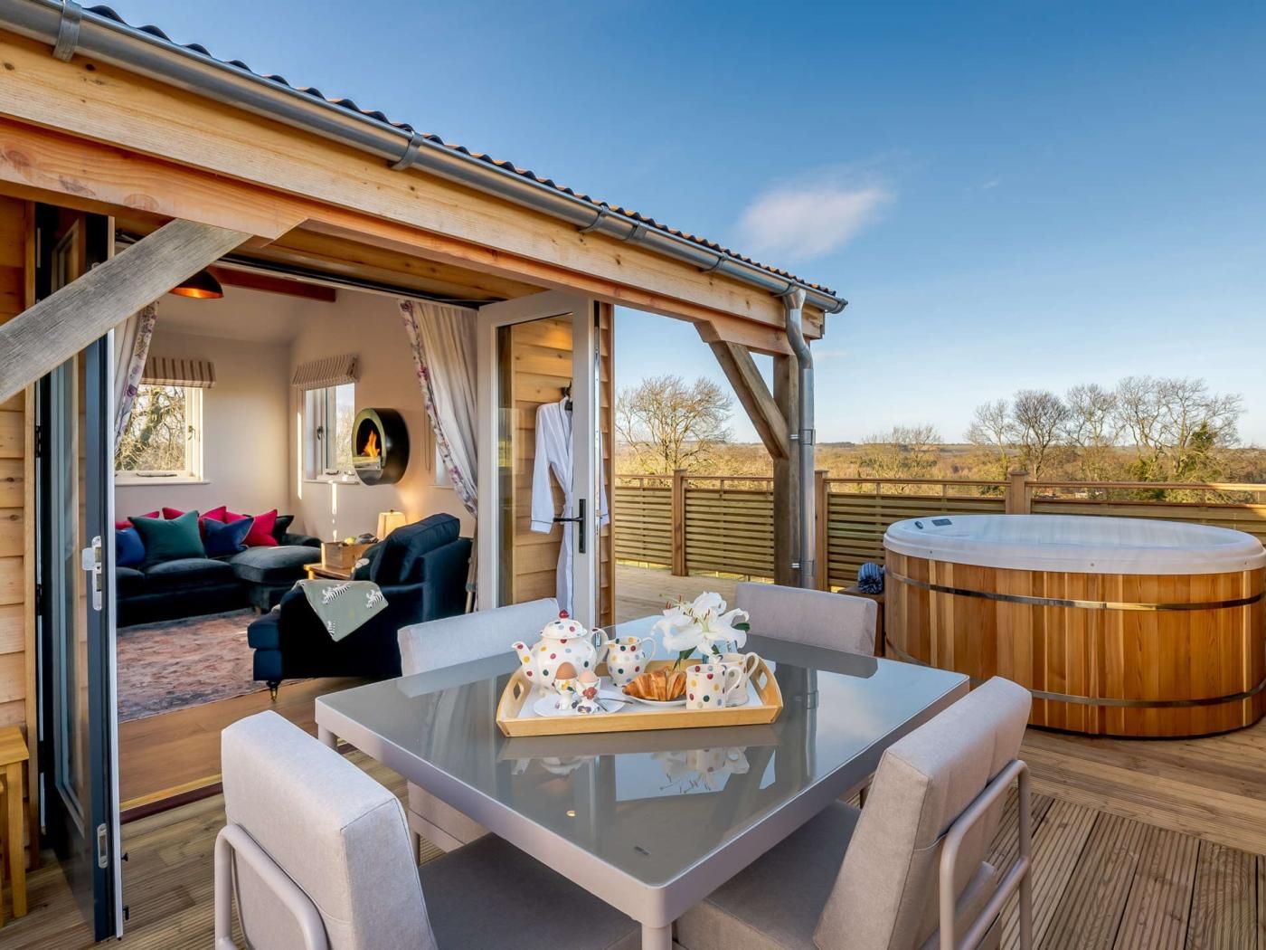 A cozy outdoor seating area with a table set for tea, a hot tub, and a wooden deck.