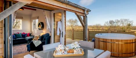 A cozy outdoor seating area with a table set for tea, a hot tub, and a wooden deck.