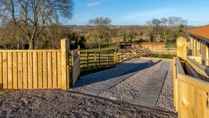 A wooden bridge leading to a stable, surrounded by trees and a clear sky. - 2 Bed in Leyburn (oc-91102) (Finghall)