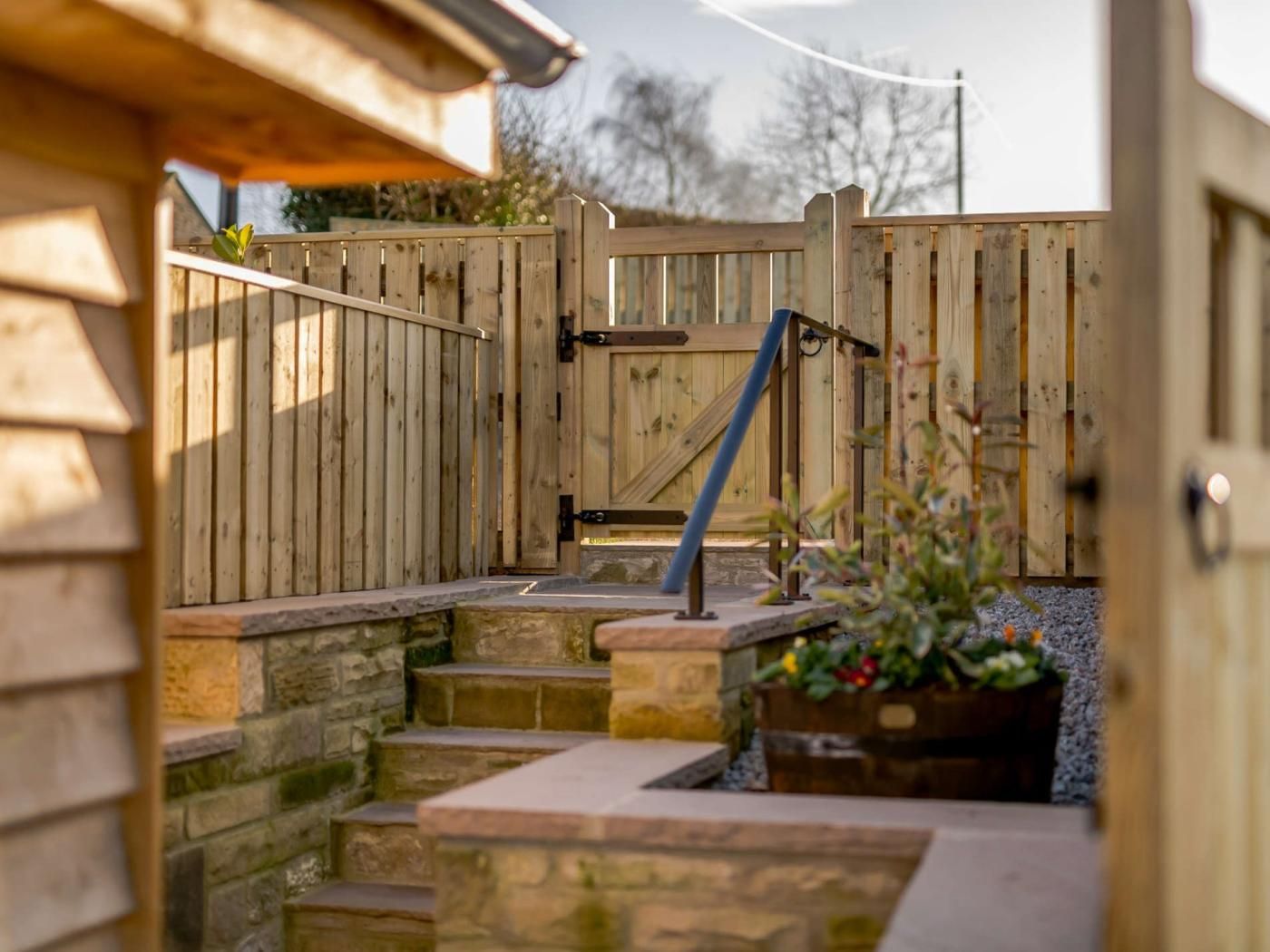 A wooden gate leading to a stone staircase with a metal handrail.