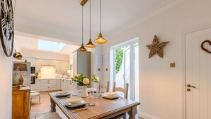 A dining area with a wooden table, chairs, and hanging pendant lights. - 2 Bed in Alnwick (oc-91316) (Alnwick)