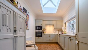 A kitchen with a herringbone floor, a skylight, and a dining area with a chair. - 2 Bed in Alnwick (oc-91316) (Alnwick)