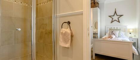 Une salle de bain avec une douche à parois de verre et une serviette accrochée au mur.