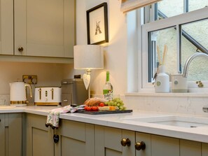 A kitchen with a white countertop, a toaster, a kettle, a bottle of Belvo, and a window with a view. - 2 Bed in Alnwick (oc-91316) (Alnwick)
