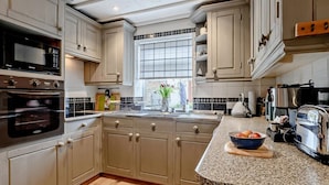 A kitchen with a large island, double ovens, a coffee machine, and a window with a view. - 2 Bed in Melton Constable (oc-91371) (Briston)