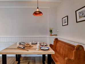A dining area with a wooden table, benches, and a hanging light fixture. - 2 Bed in Melton Constable (oc-91371) (Briston)