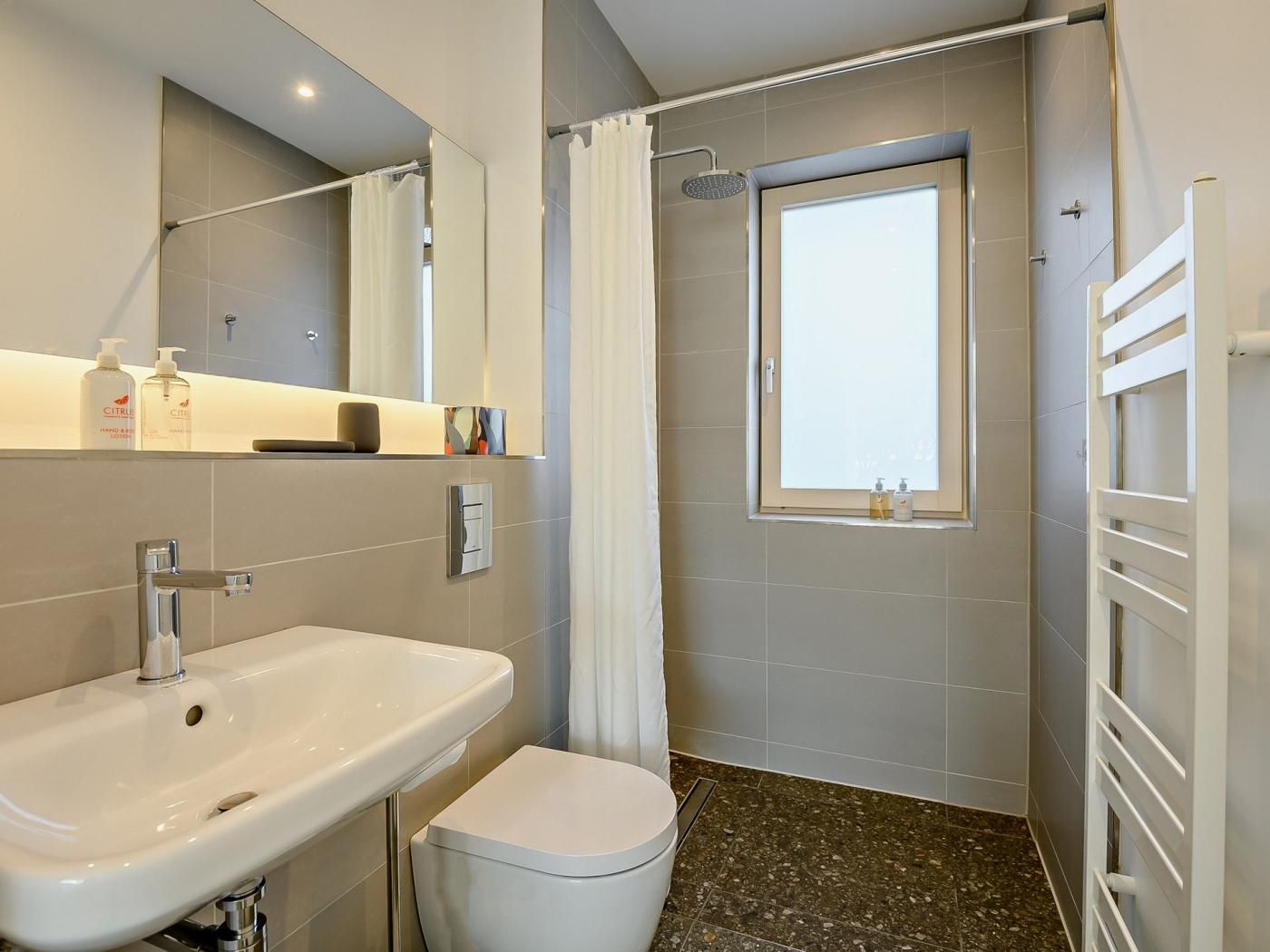 Une salle de bain avec un lavabo, des toilettes, une douche et une fenêtre.