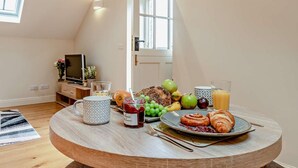 En mysig matplats med ett runt träbord, en tv och ett fönster med utsikt över staden.